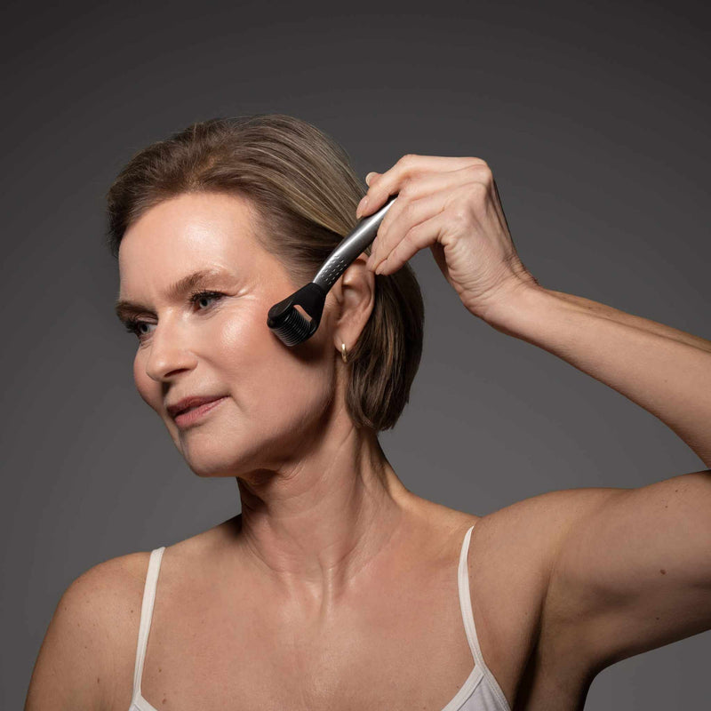 Vrouw past microneedling toe met dermaroller op gezicht, gebruikmakend van LAYZIN Anti-Aging Set met anti-aging serum.